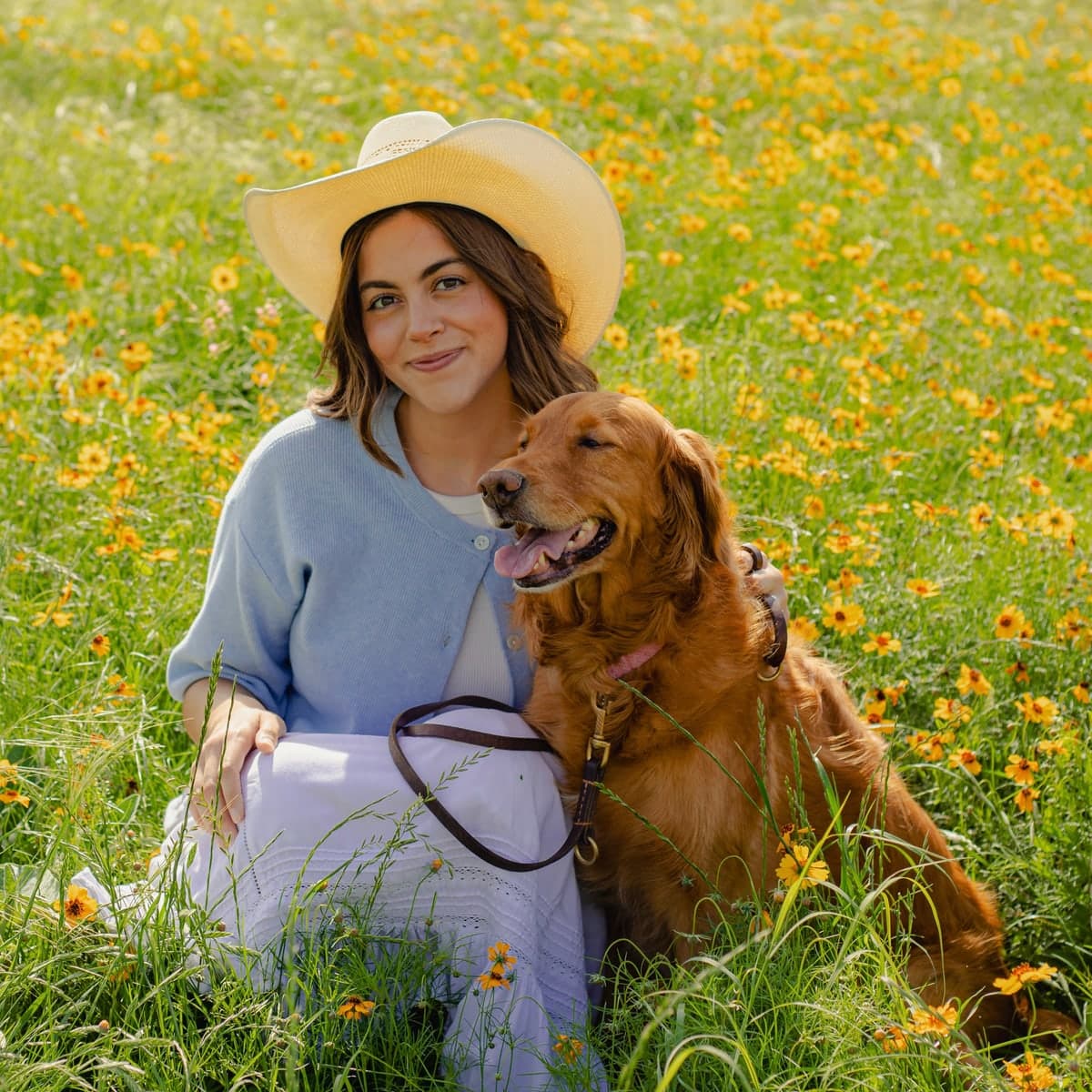 Madison, the founder of Tally, sitting in a field of yellow wildflowers with her golden retriever.
